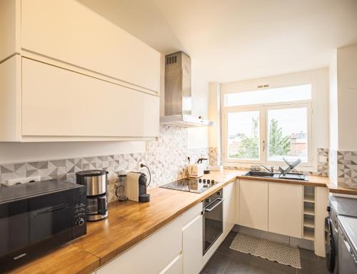 une cuisine avec des armoires blanches et une fenêtre dans l'établissement Le Central - Vue Hotel de ville - 4 Chambres, à Troyes