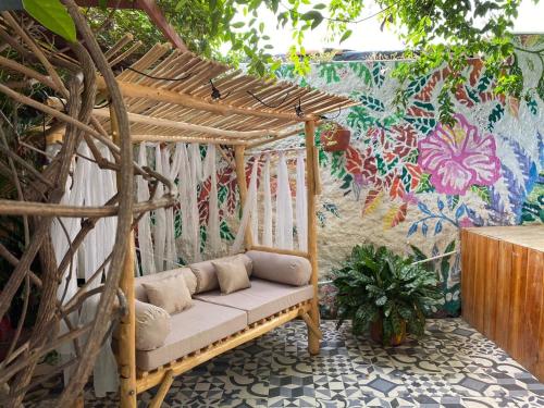 a swinging bench in a garden with a mural at Hotel Boutique Casa de Los Santos Reyes Valledupar in Valledupar