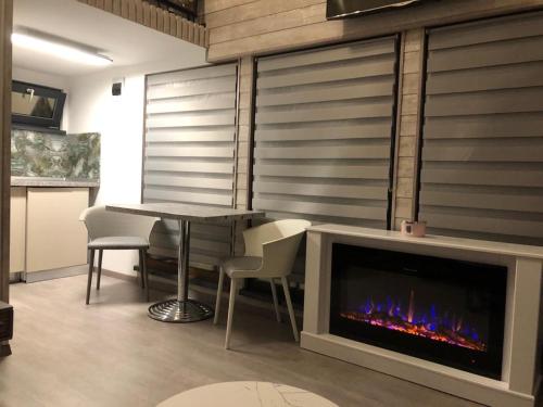 a living room with a fireplace and a table and chairs at Mini căsuța cu șemineu Moieciu in Moieciu de Jos