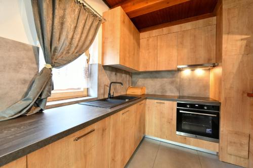 a kitchen with wooden cabinets and a sink and a window at Guest House Martin in Korana