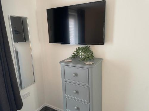 a dresser with a flat screen tv on a wall at Buckshaw Snoozy in Heapey