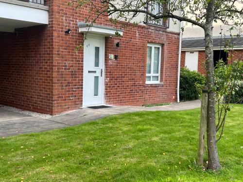 a brick house with a white door in a yard at Buckshaw Snoozy in Heapey