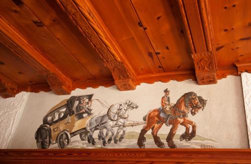 une peinture de chevaux et une voiture sur un mur dans l'établissement AlpenRetreat, à Nassereith