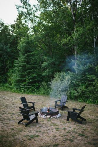three chairs around a fire pit in a park at Bay Point Hideaway in the Woods in Beulah