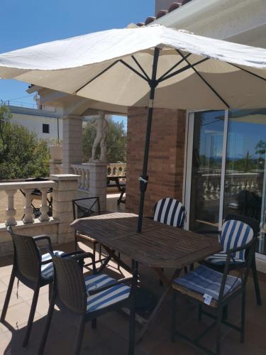 a wooden table with chairs and an umbrella on a patio at CAN TRULLEN CHALET CALAFELL in Calafell