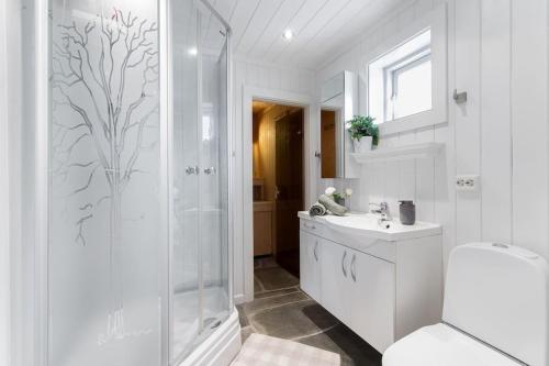 ein Bad mit einer Dusche, einem WC und einem Waschbecken in der Unterkunft Cozy cabin w/garden, BBQ, canoe, swimming, central in Sinnes