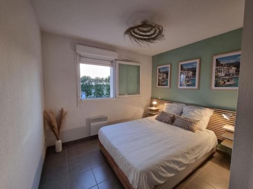 une chambre avec un lit blanc et une fenêtre dans l'établissement L'Appartement Ensoleillé, WIFI-Clim-Gare-Terrasse, à Narbonne