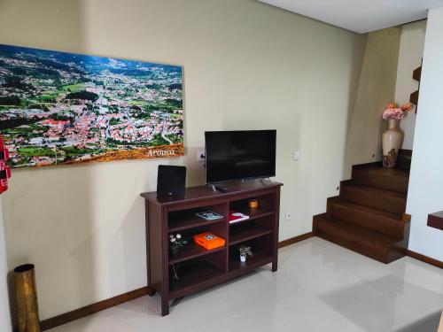 a living room with a television on a wall at Casinha da Vila in Arouca