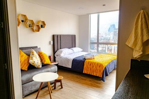 a bedroom with a bed and a couch and a window at Loft nuevo con gran vista in Bogotá