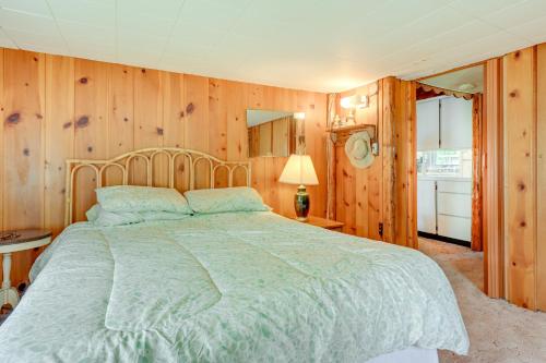 - une chambre avec un grand lit et des murs en bois dans l'établissement Gladwin Lakefront Cottage with Deck, Grill!, à Gladwin