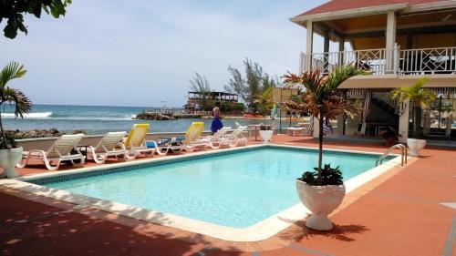 a swimming pool with chairs and the ocean in the background at Pipers Cove Resort in Runaway Bay