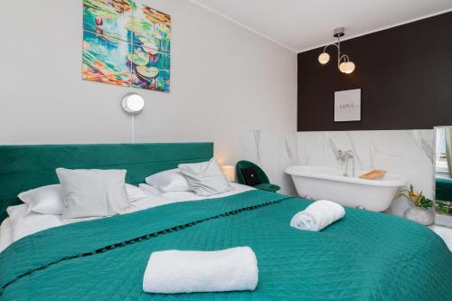 Schlafzimmer mit einem grünen Bett und einer Badewanne in der Unterkunft Przestronne 2 oddzielne sypialnie Cały apartament w spokojnej dzielnicy in Borkowo