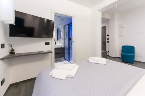 a white bedroom with a large bed with two white towels at ML luxury room in Lido di Spina