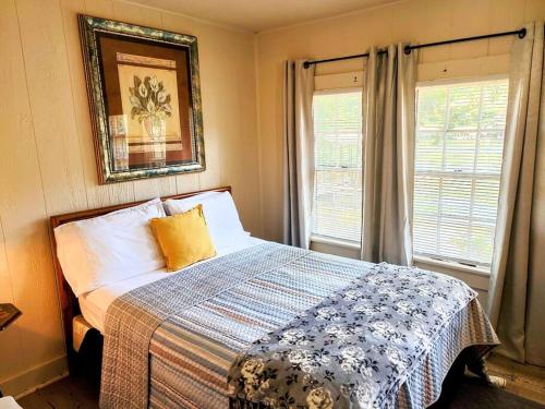 a bedroom with a bed with a blanket and two windows at #04-Adorable Large 1 Bedroom Lakeside Cottage- Pet Friendly in Hot Springs