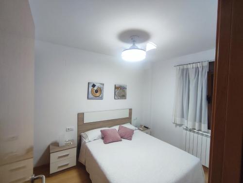 Schlafzimmer mit einem Bett mit weißer Bettwäsche und rosa Kissen in der Unterkunft Apartamento Estrella de Teruel in Teruel