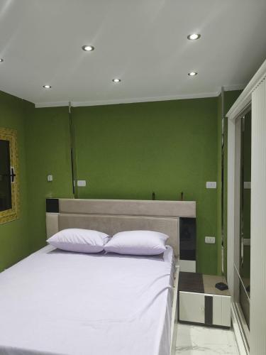 a bedroom with a white bed with green walls at الدقي in Cairo