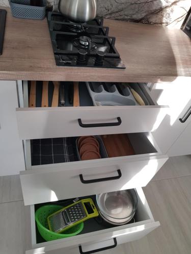 a kitchen cabinet with white drawers and a stove at Dailidžių apartamentai in Klaipėda