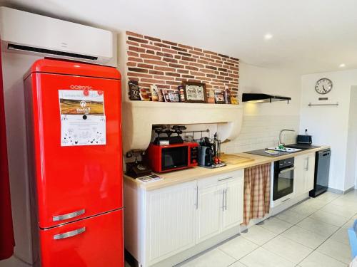 einen roten Kühlschrank in einer Küche mit Ziegelwand in der Unterkunft Gite du Moulin in Saint-Laurent-dʼAndenay