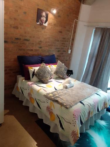 uma cama grande num quarto com uma parede de tijolos em The Eden lodge em Joanesburgo