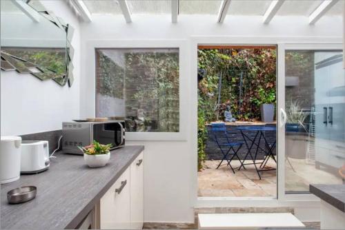 a kitchen with white walls and windows and a patio at Face aux Thermes: lit double, terrasse, wifi in Saint-Martin-dʼUriage