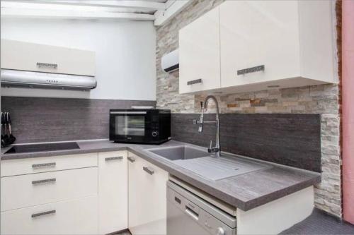 a white kitchen with a sink and a microwave at Face aux Thermes: lit double, terrasse, wifi in Saint-Martin-dʼUriage