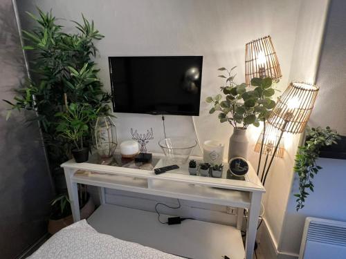 a white desk with plants and a tv on a wall at Studio moderne au cœur de Paris Batignolles in Paris