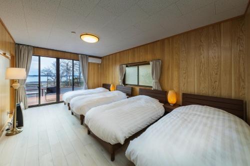 3 Betten in einem holzvertäfelten Zimmer in der Unterkunft Hermitage Resort Matsushima hibiki - Vacation STAY 14654 