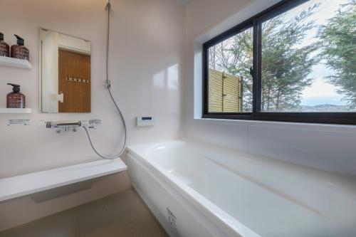 ein Bad mit einer Badewanne und einem Fenster in der Unterkunft Hermitage Resort Matsushima hibiki - Vacation STAY 14654 