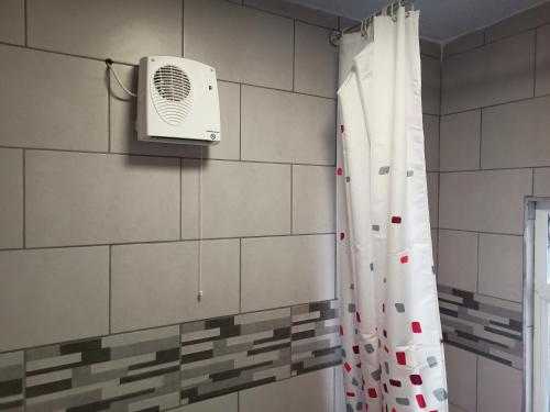 uma casa de banho com um chuveiro e uma ventoinha na parede em Brand New Cosy Apartment 3 Sleep, Garden access Free Wi-Fi & Parking em Newport