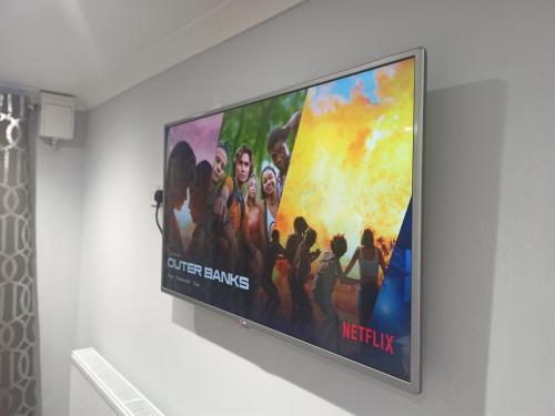 a large flat screen tv hanging on a wall at Newport rental property Furnished studio near train station Free Wifi Parking in Newport