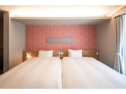 duas camas num quarto com uma parede vermelha em Hotel Celeste Shizuoka Takajo - Vacation STAY 94099v em Shizuoka