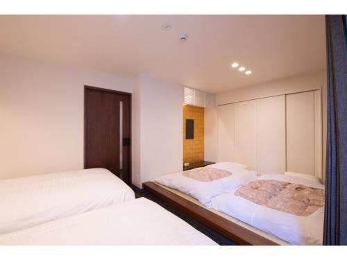 Hotel Celeste Shizuoka Takajo - Vacation STAY 94075v في شيزوكا: غرفة نوم بسريرين مع شراشف بيضاء ومرآة