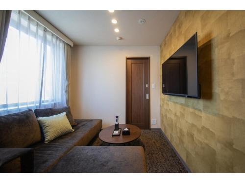 a living room with a couch and a television on a wall at Hotel Celeste Shizuoka Takajo - Vacation STAY 94075v in Shizuoka