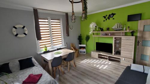 een woonkamer met groene muren en een tafel met stoelen bij Stylowy apartament w Gdyni z bezpłatnym parkingiem i niedaleko plaży in Gdynia