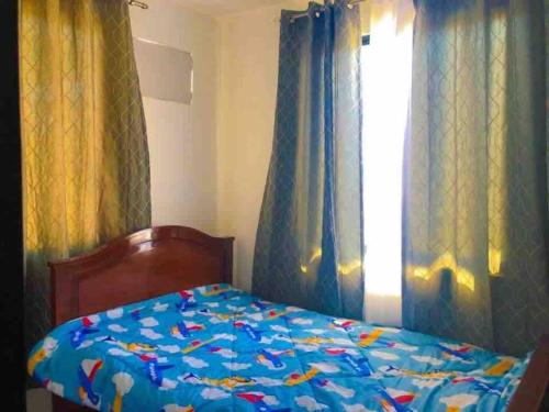 a bed in a bedroom with curtains and a window at 3 Bedroom Furnished House near SM CDO uptown in Cagayan de Oro