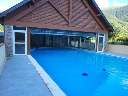 une grande piscine avec une maison en bois dans l'établissement Appartement T3 5 Pers Domaine Les PIC D'ARAN, à Luchon