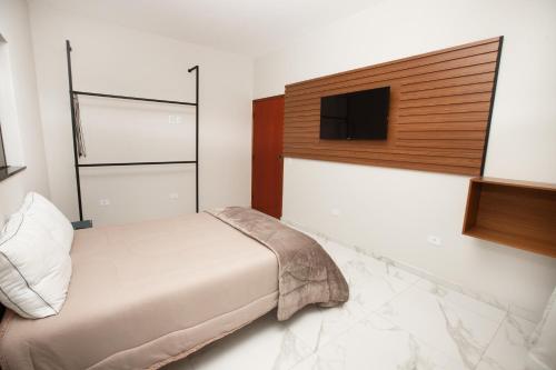 um quarto com uma cama e uma televisão de ecrã plano em ECOLETRAS APART - HOTEL - SÃO THOMÉ DAS LETRAS Mg em São Tomé das Letras