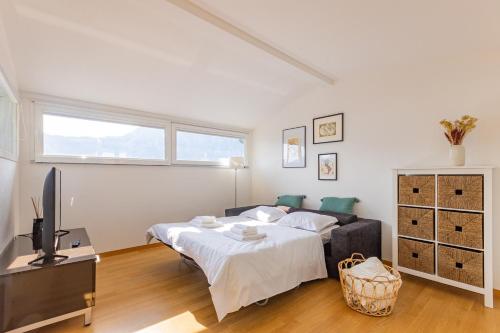 um quarto branco com uma cama e uma televisão em Casa Elea_ Panoramic Attic in City Center em Campione dʼItalia