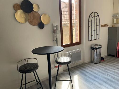 - une table et deux tabourets dans une pièce avec fenêtre dans l'établissement Le Citadin, à Sens