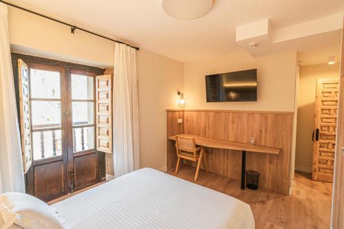a bedroom with a bed and a desk and a television at Hotel BESTPRICE Santillana in Santillana del Mar