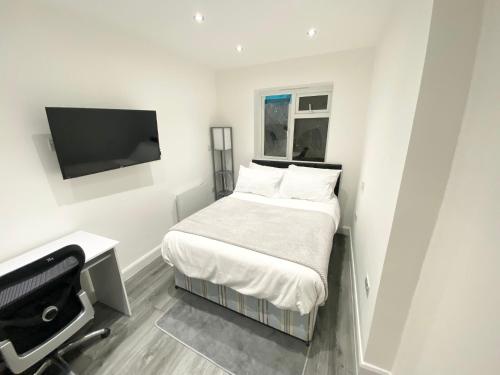 um pequeno quarto com uma cama e uma televisão de ecrã plano em London Studio em Chingford