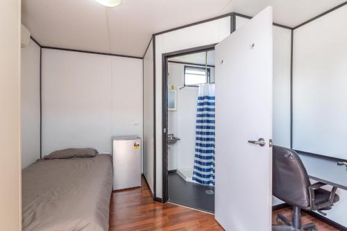 a bedroom with a bed and a desk and a chair at Magnolia Village Caravan Park in Hervey Bay