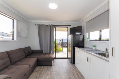 a living room with a couch and a kitchen at Magnolia Village Caravan Park in Hervey Bay