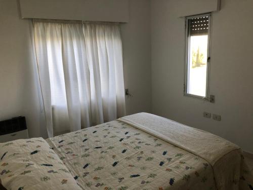 1 dormitorio con cama con edredón y ventana en Sans Souci en Gualeguaychú