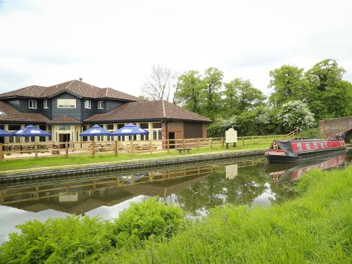 a house with a boat in the water next to a river at Cuttle Bridge Inn Hotel - NEC / Birmingham Airport in Minworth