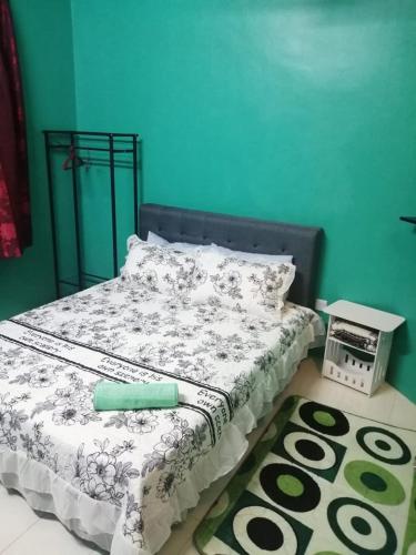 ein Bett mit einer schwarzen und weißen Bettdecke und einem Teppich in der Unterkunft Iman Guesthouse in Jitra