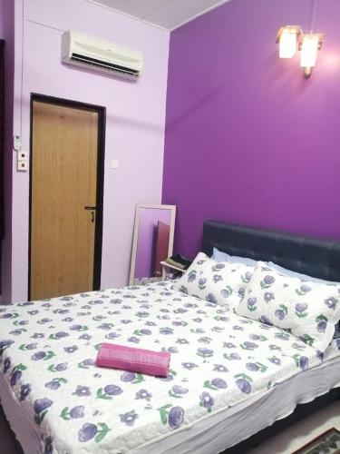 ein Schlafzimmer mit einem Bett mit einer lila Wand in der Unterkunft Iman Guesthouse in Jitra