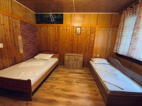Duas camas num quarto com paredes de madeira em Къщи за гости Армагански път em Kazanluk