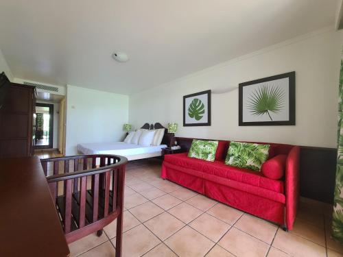 a living room with a red couch and a bed at Studio village vacances sainte luce C6 in Sainte-Luce