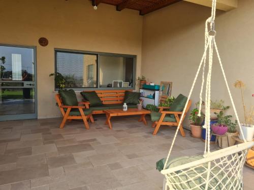 eine Terrasse mit Stühlen und einer Schaukel in der Unterkunft פינה קסומה בגליל in Kibbuz Dafna